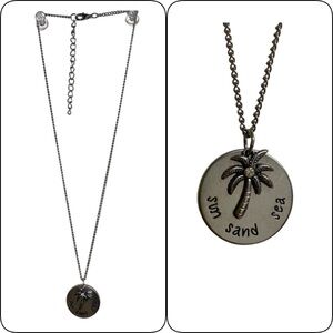 Necklace with silver tone disc that reads “sun sand sea”. Palm tree char…